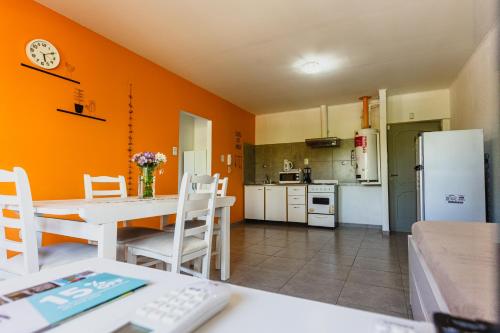 cocina con pared de color naranja, mesa y sillas en Céntrico Departamento Tangerine San Rafael en San Rafael