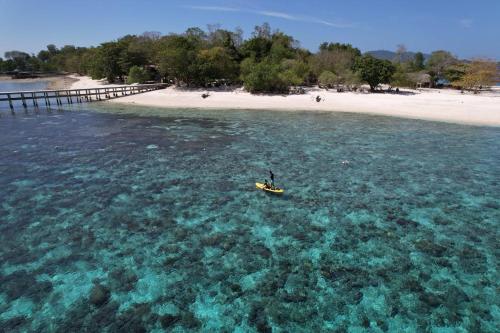 a person in a kayak in the water near a beach at homestay noah in Likupang