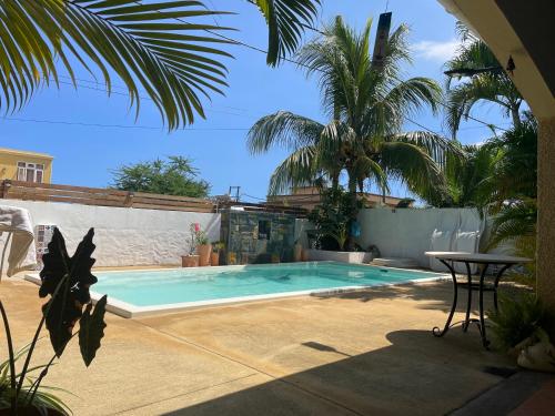 a swimming pool with a table and palm trees at JayKay_PrivateRoom_FlicEnFlac in Flic-en-Flac