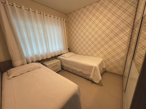 ein kleines Zimmer mit zwei Betten und einem Fenster in der Unterkunft Costa do Marfim - Bombinhas in Bombinhas