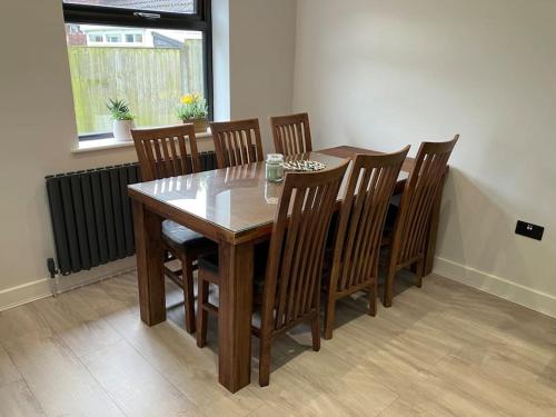 a dining room table with wooden chairs and a table and a window at Newly renovated, modern bungalow - quiet location in Lytham St Annes