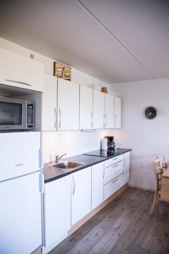 a kitchen with white cabinets and a sink and a microwave at Hotel Tannishus in Bindslev