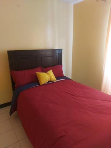 a bedroom with a red bed with two yellow pillows at Mrembo Lovely Nest in Nairobi