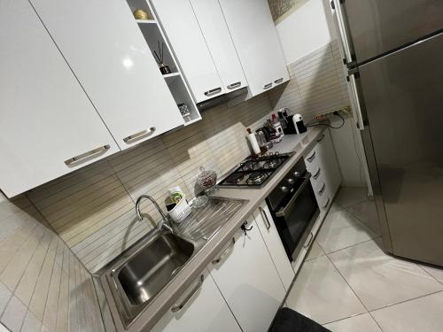 a white kitchen with a sink and a stove at Sindi's Daily Apartment in Durrës