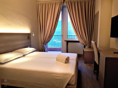 una camera d'albergo con letto, scrivania e finestra di Hotel Bazzoni a Tremezzo