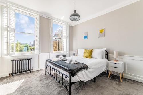 a bedroom with a bed and two windows at Pass the Keys Luxury Converted Victorian Flat in Leafy Highbury in London