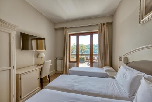a hotel room with two beds and a window at Hotel Bazzoni in Tremezzo