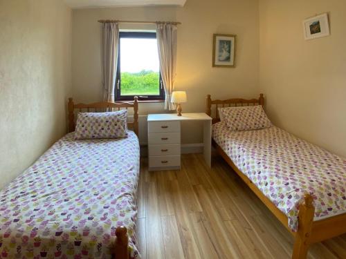 two twin beds in a bedroom with a window at Cottage 383 - Claddaghduff in Claddaghduff