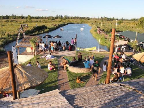 a group of people sitting on the grass by a river at Complejo Balloffet in San Rafael