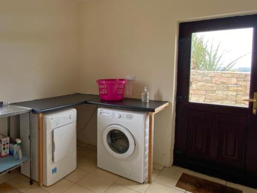 a laundry room with a washing machine and a pink bucket on a counter at Cottage 383 - Claddaghduff in Claddaghduff
