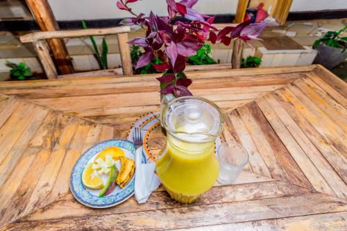 a glass jar of orange juice next to a plate of food at The Secret Garden Hotel Moshi in Moshi