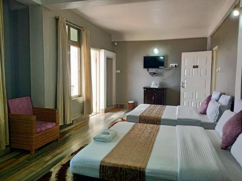 a hotel room with two beds and a chair at FALL VIEW HOMESTAY in Cherrapunji