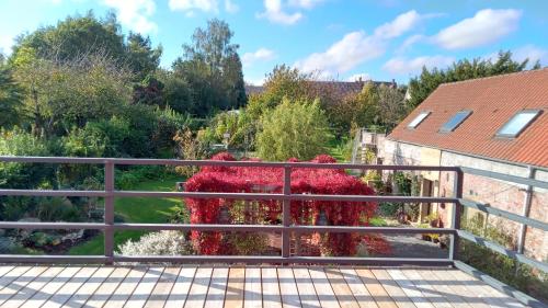 uma vista a partir da varanda de um jardim com flores vermelhas em Au Duc de Sep em Sepmeries