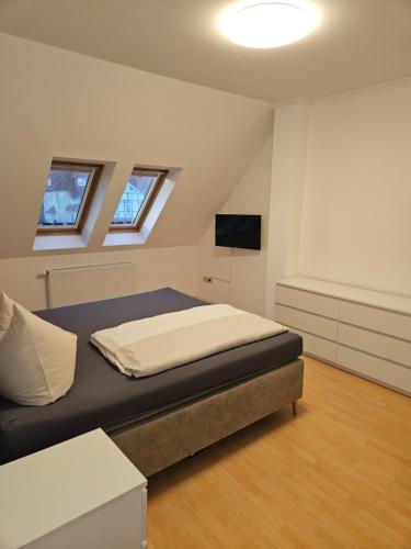 a bedroom with a bed and two windows at Heilotel in Heilbad Heiligenstadt