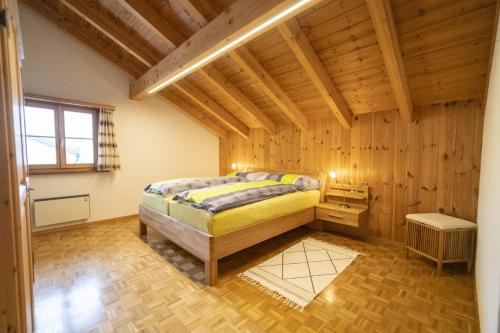 - une chambre avec un lit dans une pièce dotée de murs en bois dans l'établissement Chasa Sur Chafarrer, à Scuol