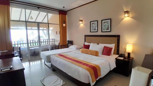 a hotel room with a large bed and a balcony at Laya Beach in Wadduwa