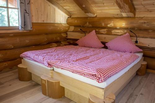 uma cama num chalé de madeira com duas almofadas em Blockhaus Almhütte Hofblick em Glatten