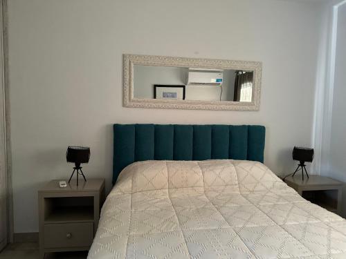 a bedroom with a bed with a blue headboard and a mirror at Departamento chic en el corazón de Mendoza in Mendoza