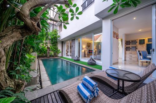 an indoor pool with a table and chairs next to a house at Villa Nora, by Five Elements in Canggu