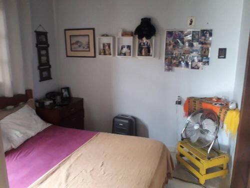 ein Schlafzimmer mit einem Bett und einem Ventilator sowie Bildern an der Wand in der Unterkunft Casa próximo a praias, trilhas e cachoeiras. in Garopaba