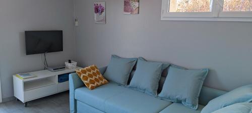 a living room with a blue couch and a tv at L'Ansolane in Fuveau