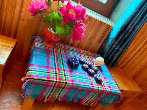 une table avec un vase avec des fleurs roses dans l'établissement Lý Đạch Homestay&Bungalow, à Làng Me
