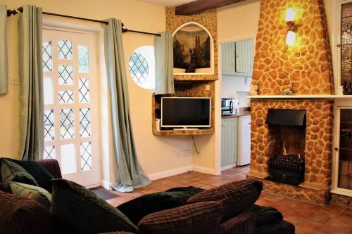 Cosy Countryside Cottage - Hot Tub & Dog friendly في Castle Rising: غرفة معيشة مع أريكة ومدفأة