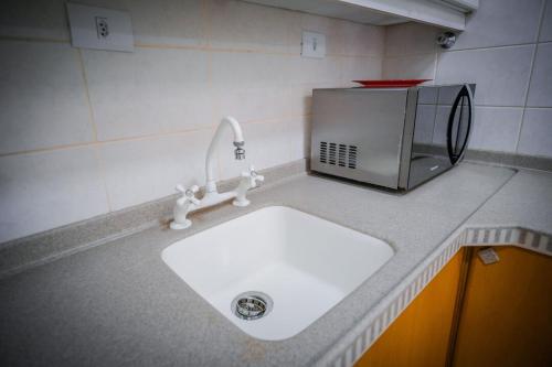 um balcão de cozinha com um lavatório e um micro-ondas em Apto com WiFi no centro de Aguas De Lindoia SP em Águas de Lindoia