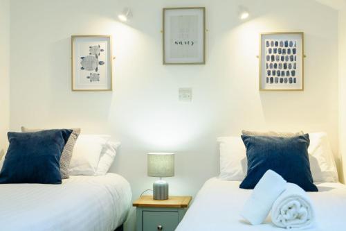 two beds with blue pillows in a bedroom at Porthallow in Budock Water