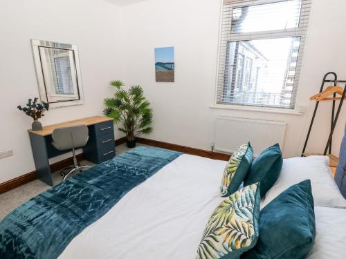a large bed in a room with a desk at 36A Mary Street in Porthcawl