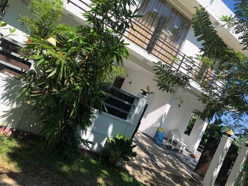 a white house with a tree in front of it at Lanka Villa Mirissa in Mirissa