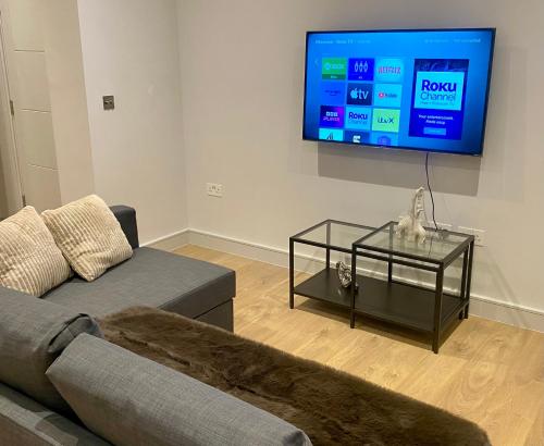 een woonkamer met een bank en een tv aan de muur bij Modern & Luxury Flat in Sutton