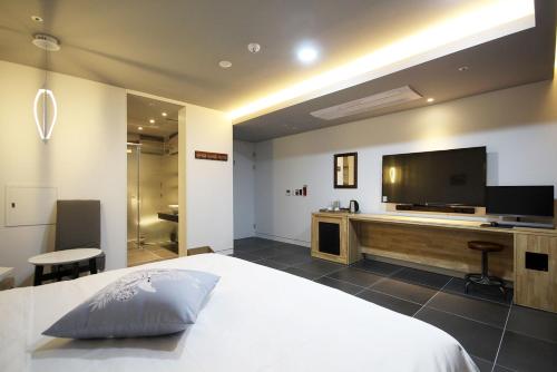a bedroom with a large bed and a flat screen tv at Ulsan Samsan Pandora Hotel in Ulsan