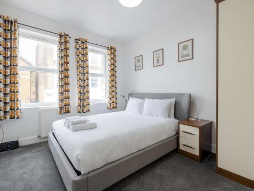 a bedroom with a white bed and two windows at Pass The Keys - Homely flat in east London with sunny Balcony in London