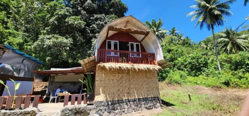 una pequeña casa con techo de paja en homestay noah, en Likupang