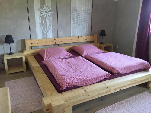 ein Holzbett mit lilafarbener Bettwäsche und Kissen darauf in der Unterkunft Bauniglerhof in Riedering