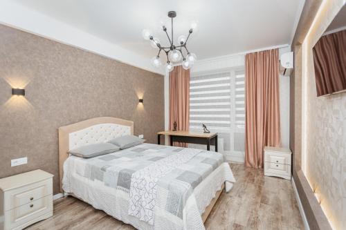 een slaapkamer met een wit bed en een kroonluchter bij Comfortable apartments. Good location. in Chişinău