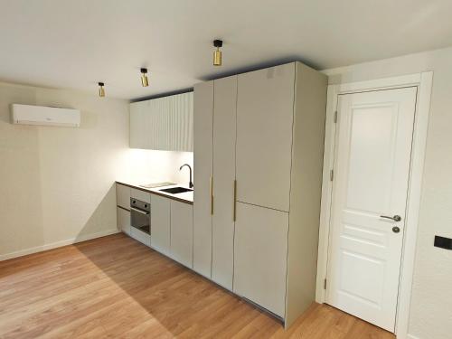 a kitchen with white cabinets and a door at Luna Palanga in Palanga