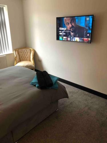 a bedroom with a bed and a tv on the wall at Entire 2 bed modern apartment in Nantwich