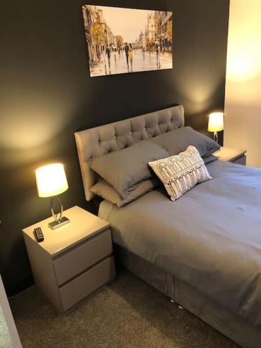 a bedroom with a bed and a nightstand with a lamp at Entire 2 bed modern apartment in Nantwich