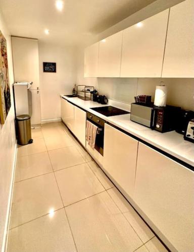a kitchen with white cabinets and a refrigerator at H1: Stunning Large Apt - Under 100m to Piccadilly Circus! in London