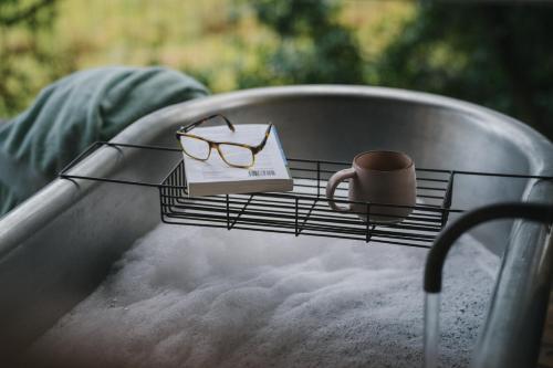 a table with glasses and a mug and a book at RewildThings Treehouses in Gloucester