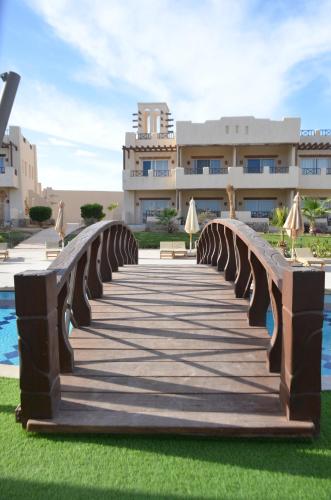 a wooden bridge with umbrellas in front of a building at True Beach Resort in Marsa Alam City