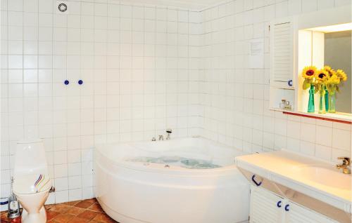 uma casa de banho branca com uma banheira e um lavatório em Amazing Home In Krus With 3 Bedrooms, Sauna And Wifi em Rønsheved
