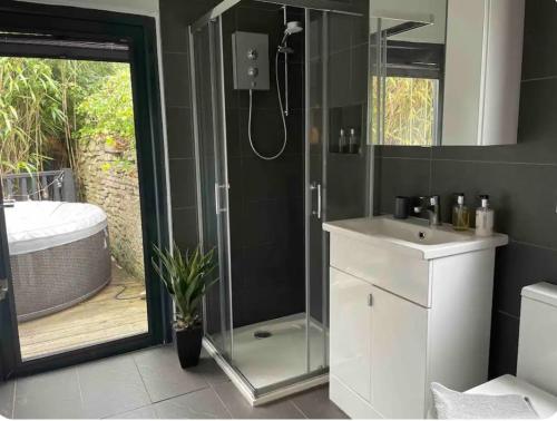 a bathroom with a shower and a sink and a tub at 1 bedroom rural cabin retreat with hot tub in Hambrook close to Bristol city centre in Bristol