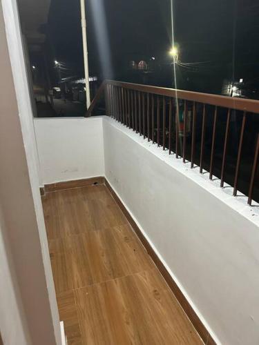 einen Balkon mit weißem Geländer und Holzböden in der Unterkunft Brindalay 2-Apt in Heart of Tsk! in Tinsukia
