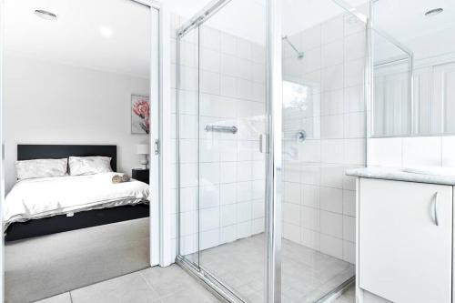 a bathroom with a glass shower and a bed at Suburb best family house Melbourne east in Boronia