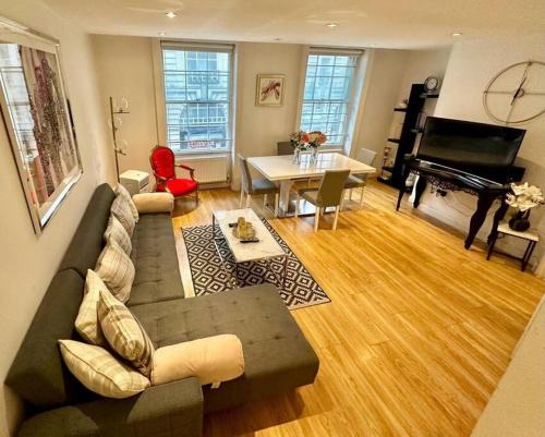 a living room with a couch and a piano at Haymarket 2: Large Central Apt! in London