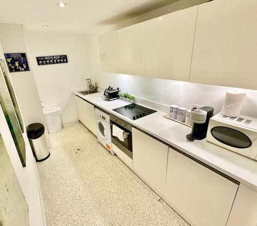 a white kitchen with a sink and a microwave at Haymarket 2: Large Central Apt! in London