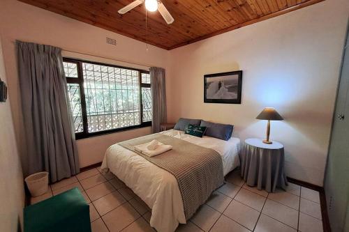 a bedroom with a large bed and a window at Lovely 3 Bedroom house near the beach. in Port Edward